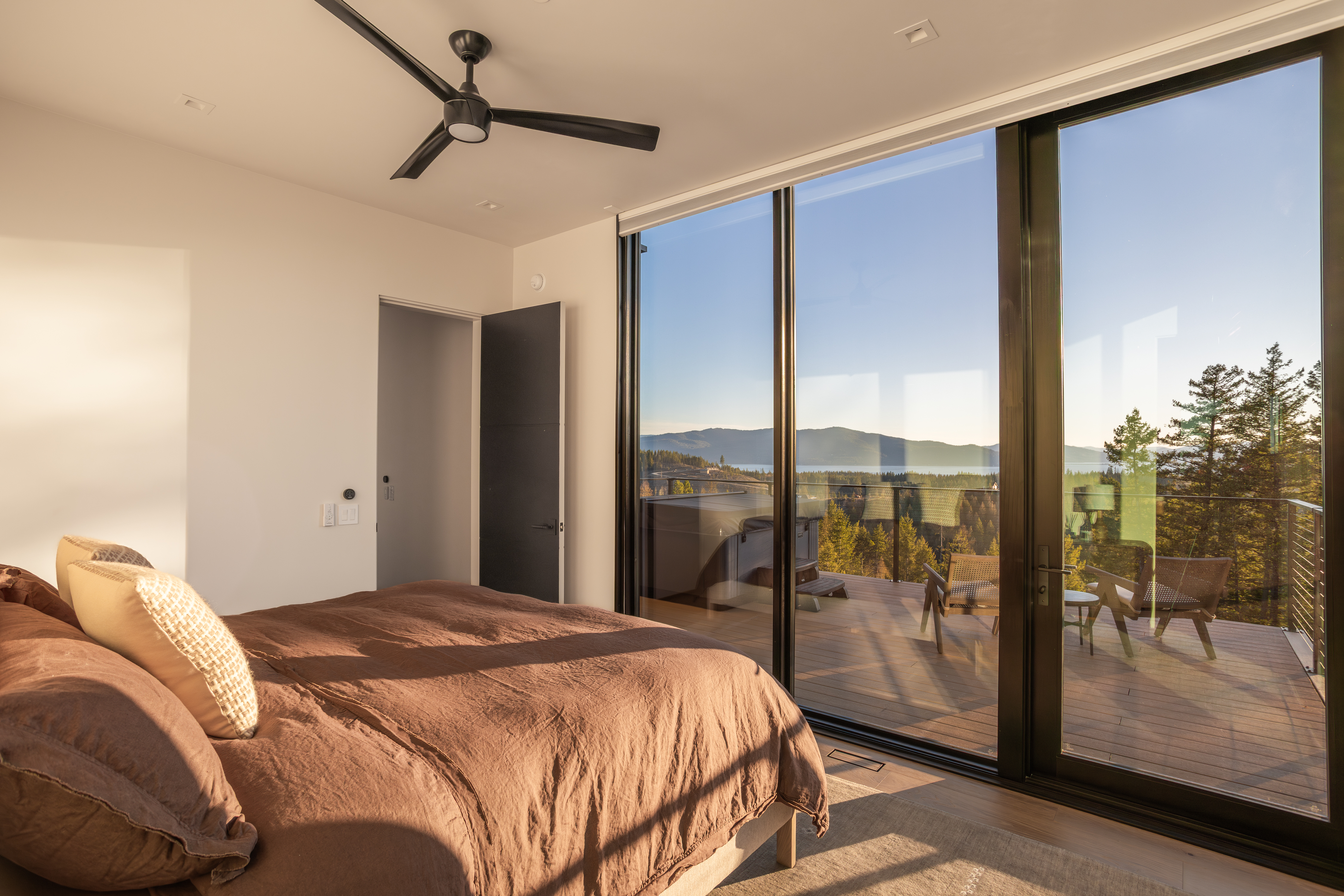 Bedroom with brown bedding, a ceiling fan, and sliding doors opening to a deck.